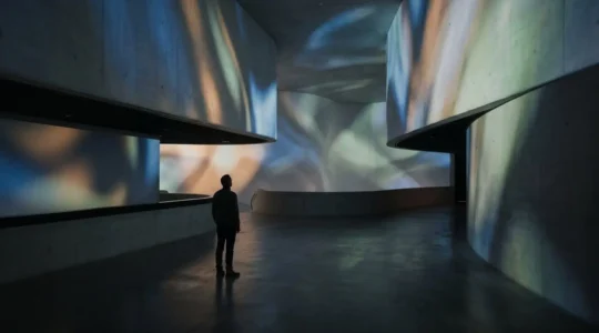 Visiteur dans un espace d'exposition immersive avec projection lumineuse et ambiance contemplative